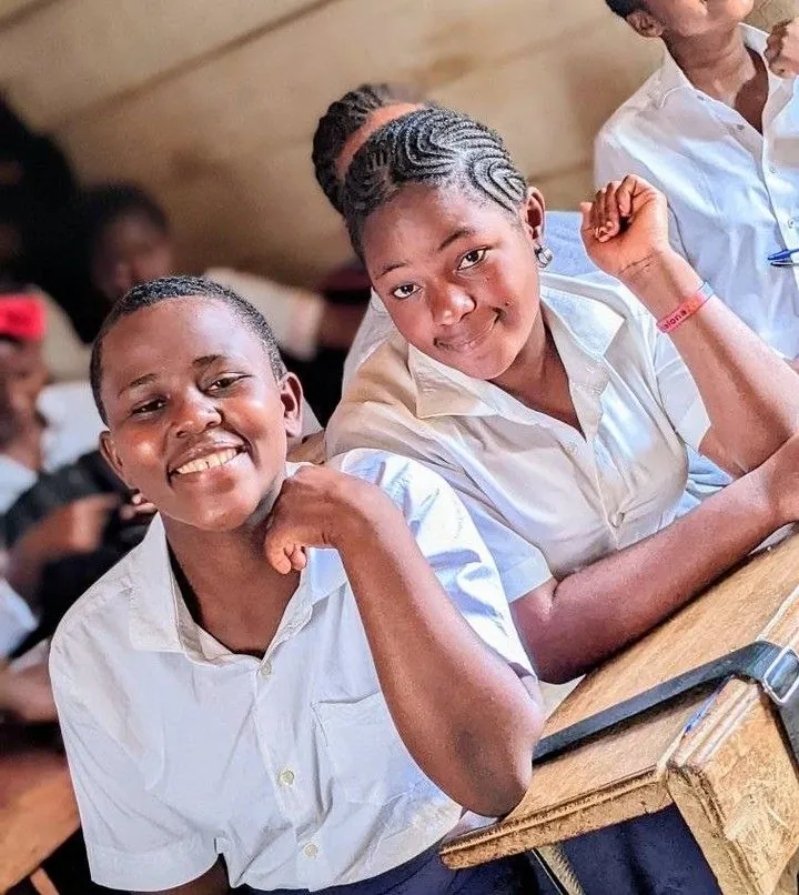 Two schoolgirls smiling in a classroom